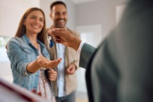 Close up of happy couple receiving keys of their new home from real estate agent. 