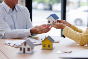 Estate business agent giving house Real estate transaction with agent giving house keys to client over a contract